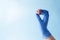 A hand in a blue medical glove holds coronavirus ball model on a blue background