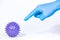 Hand in a blue medical glove scares and threatens by pointing finger purple virus ball on a white background