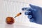 A hand in a blue medical glove stuck a syringe with an orange liquid into a spoiled tangerine. Bioengineering concept, GMO