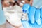 Hand in blue medical gloves holding small vial with label Coronavirus vaccine own sticker design, not real product, blurred face