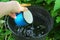 Hand with a blue mug takes water from a black bucket