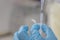 A hand with blue nitril glove holding a plastic eppendorf tube and a part of a micropipet taking liquid out of the tube.