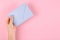 Hand with blue paper envelope composition on pink background