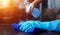 Hand in blue rubber glove holding blue microfiber cleaning cloth and spray bottle with sterilizing solution make cleaning