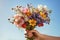 Hand with bouquet of beautiful wild flowers in the summer sun