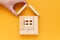 Hand builds a house of wooden blocks on a yellow background. housing, family