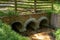 Hand built red brick headwall with three large concrete drainage pipes, muddy water environmental hazard