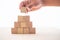 The hand of the businessman caught the wooden blocks placed on a white background as a house to show the stability of doing