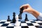 Hand of businessman moving chess in competition with sky background, shows leadership, followers and business success strategies