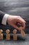 The hand of a businessman puts a wooden figure of a man in a row to other employees. The concept of business management