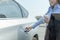 Hand of  businesswoman opening a car door and left hand hold cup of coffee and tablet