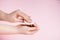 Hand care concept. Young woman remove nail polish on pink background. Place for text