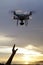 Hand catching drone aircraft in sunset sky