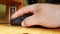 Hand of a Caucasian man working with the mouse on a wooden table, remote work, freelancer, workplace