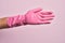 Hand of caucasian young man with cleaning glove over isolated pink background stretching and reaching with open hand for