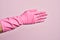 Hand of caucasian young man with cleaning glove over isolated pink background stretching and reaching with open hand for