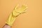 Hand of caucasian young man with cleaning glove over isolated yellow background presenting with open palm, reaching for support