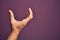 Hand of caucasian young man showing fingers over isolated purple background picking and taking invisible thing, holding object