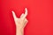 Hand of caucasian young man showing fingers over isolated red background picking and taking invisible thing, holding object with