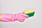 Hand of caucasian young woman wearing cleaning glove holding scourer sponge over isolated white background