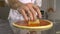 Hand chef puts cheese in pizza base on tomato sauce closeup