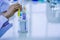 Hand of chemist Holds a chemical tube to experiment with colorful fluids in glass tubes placed on table