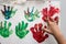 Hand of a child making red and green colourful palm prints