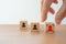 Hand choose red person and focus sign on wooden cube block with blurred others