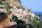 Hand with classic compass on background of summer resort landscape with European architecture and blue sea as symbol of tourism wi