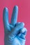 Hand with cleaning glove making fist. Hand in a rubber glove on a pink background. vertical photo