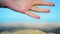 Hand closeup of releasing sand. The sand flows through the hands against a blue ocean. Summer beach vacation.