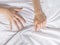 Hand clutches grasps a white crumpled bed sheet in a hotel room, a sign of ecstasy, feeling of pleasure or orgasm