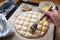 Hand is coating flat bread dough with an egg yolk mixtur, baking in the style of the Turkish Ramadan Pide