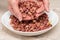 Hand collects peanuts from a pile of peanuts in a white plate. Healthy eating concept