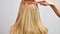 Hand is combing healthy long straight hair. Haircare. Beautiful and smooth blonde hair