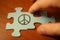 Hand connects puzzles of sign of peace. World Day of Peace.