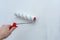 Hand with a construction roller in the process of priming the wall. The concept of renovation and decoration of the room.