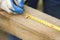 Hand of a construction worker points with a pencil the distance on a wooden edge.