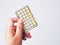 Hand with contraceptive pill panel, birth control pills on wooden table