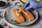 The hand of the cook that puts a branch of rosemary on the salmon fillet