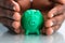 Hand Covering The Green Piggybank