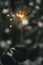 Hand in cozy mitten holding burning sparkler on background of pine tree branches in snow. Happy New Year! Atmospheric magic moment