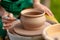 Hand craft making pottery on wheel. Female hands mold ceramic plate from clay pot