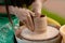 Hand craft making pottery on wheel. Female hands mold ceramic plate from clay pot