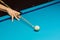 Hand with cue stick pointing at a ball on billiard table