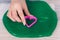 Hand cutting a green slime with purple plastic heart cookie cutter on a table