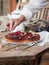 hand delicately decorating a fig tart with fresh edible flowers