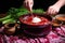 hand delicately placing a hearty pot of borscht onto a placemat