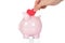 Hand deposit red heart in piggy bank