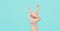 Hand is devil horns or rock hand sign and have foam soap bubbles on a green mint or Tiffany Blue background.isolated